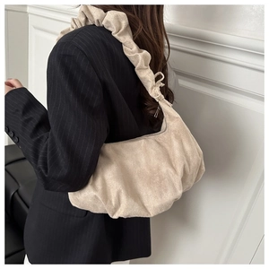 Close-up of beige suede dumpling bag worn by model in a black striped blazer