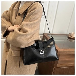 Detail of black glossy leather underarm bag with silver buckle and horizontal stitching
