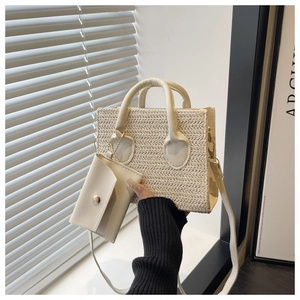 Detail of cream woven tote bag with matching coin purse charm and leather handles