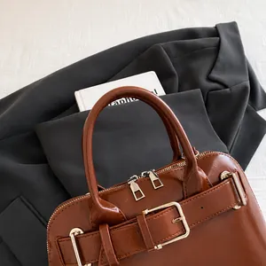 Detail of a brown glossy shell bag with silver hardware and a comfortable handle