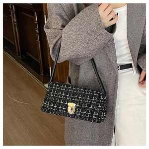Detail of tweed underarm bag with gold lock and black strap on professional attire