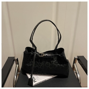 Détail de la texture léopard sur le sac porté épaule en daim noir avec boucle métallique dorée