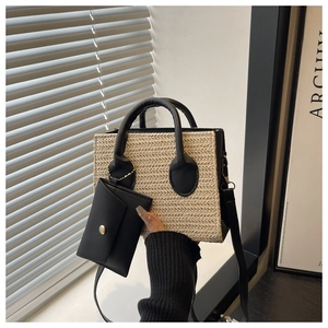 Detail of woven straw handbag with black leather handles and detachable small pouch