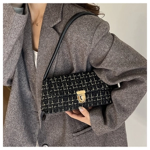 Detail of tweed shoulder bag with gold hardware buckle and black woven fabric texture