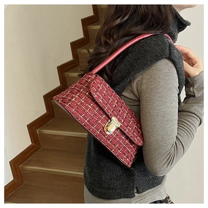 Detail of red tweed shoulder bag with gold clasp and leather strap on model