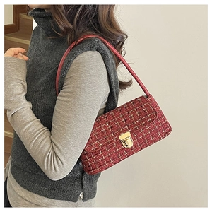 Detail of red tweed shoulder bag with gold metal clasp and woven texture