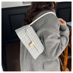 Detail of white tweed underarm bag with gold hardware and woven metallic texture