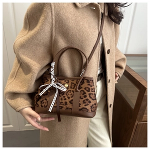 Close-up of leopard print bucket bag with luxury brand style ribbon and leather strap