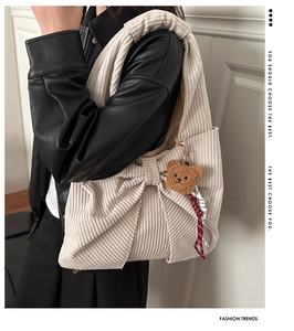 Détail du sac à bandoulière en velours côtelé beige avec nœud et breloque ours
