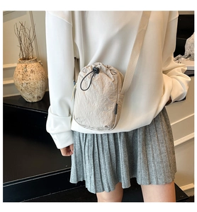 Detail of off-white nylon mini crossbody bag with drawstring closure and shoulder strap