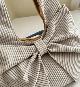 Close-up of ribbed corduroy fabric texture and large decorative bow on the handbag