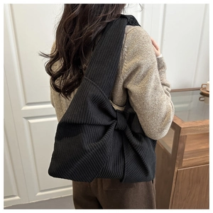 Détail du sac à bandoulière en velours côtelé noir avec nœud papillon élégant sur l'anse