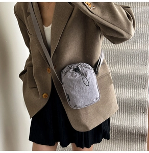 Outdoor mini grey nylon crossbody bag with drawstring closure shown on shoulder