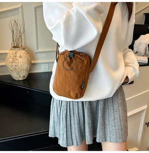 Brown nylon crossbody bag for cell phone with adjustable strap shown on model outdoors