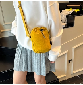 Detail of lightweight bright yellow nylon mini crossbody bag with adjustable strap and tag
