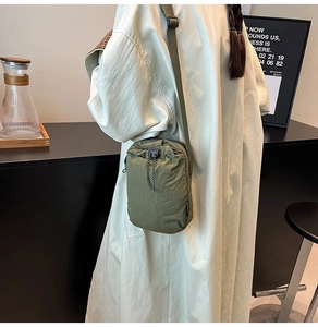 Army green nylon mini crossbody bag with drawstring closure worn by a model in a casual setting