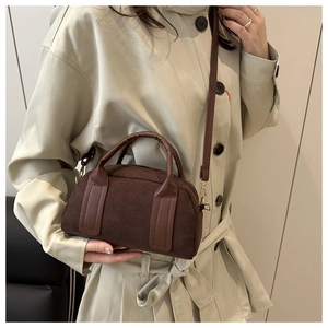Detail of dark brown suede Boston bag with gold hardware and adjustable shoulder strap