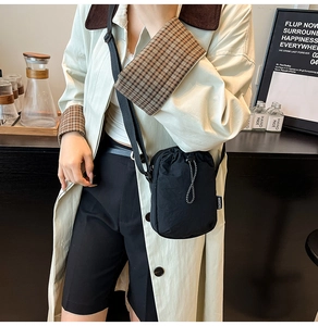 Close-up of lightweight black nylon crossbody bag with drawstring closure and fashion tag