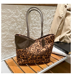 Detailopname van luipaardprint shopper met leren bies op houten standaard