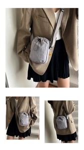 Detail of gray nylon crossbody bag with drawstring closure and adjustable strap on a model