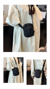 Detail of black nylon drawstring crossbody bag with adjustable strap and fashion label