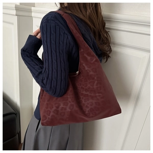 Dettaglio della grande borsa tote bordeaux con stampa leopardata portata sulla spalla