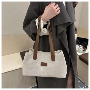 Detail of canvas tote bag showing cream fabric texture and brown leather straps