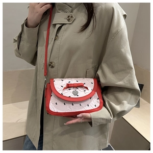 Détail du nœud rouge et pendentif cœur sur sac baguette blanc à imprimé floral