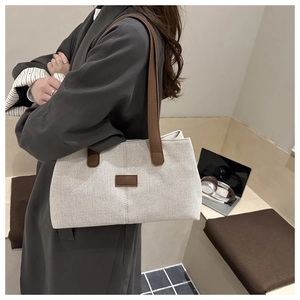 Detail showing high-capacity linen shoulder bag with brown leather trim and shoulder strap