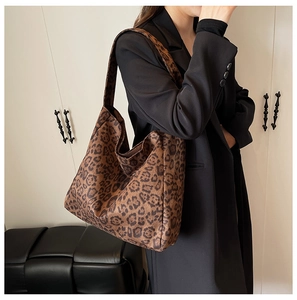 Detailed view of leopard print tote bag with wide strap on shoulder of black blazer