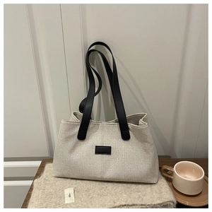 Linen shoulder bag with black leather straps on a minimalist rustic white wood backdrop