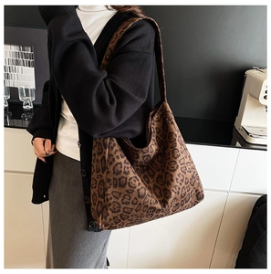 Detailed view of leopard print tote bag with wide strap on model in indoor setting