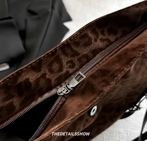 Detailed macro shot of the smooth metal zipper on a brown leopard print tote bag