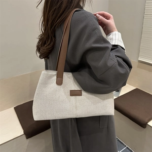 Linen patchwork tote bag with brown leather straps shown from a stylish side view