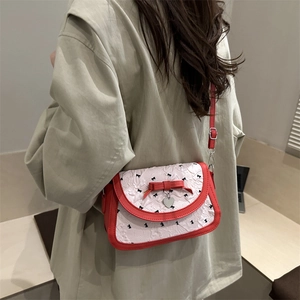 Sac bandoulière nœud rouge et blanc avec pendentif cœur porté par le mannequin