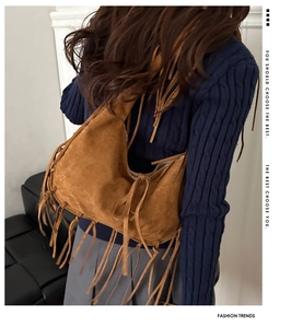 Detalle del bolso de hombro de ante marrón con flecos combinado con un atuendo informal