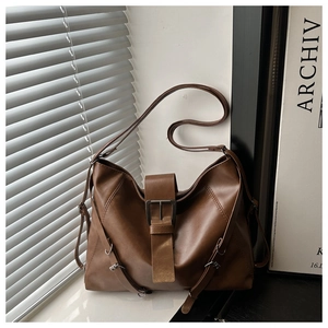 Detail of caramel brown PU leather tote bag with metallic buckle and boho style straps