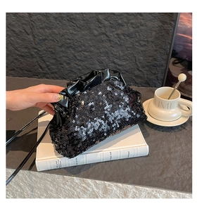 Detail of black sequined cloud bag featuring a glossy pleated closure and chain strap