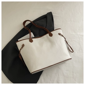 Vue détaillée du sac cabas en cuir litchi blanc avec anses marron sur tissu blanc