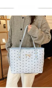 Détail du sac fourre-tout matelassé bleu clair avec motifs nœuds noirs et fermoir doré