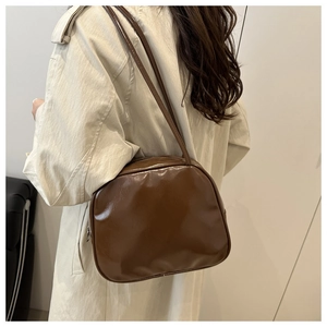 Brown glossy PU leather shoulder bag styled with a beige trench coat for everyday wear