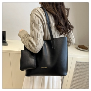 Macro view of black leather tote bag with gold lettering and matching small pouch