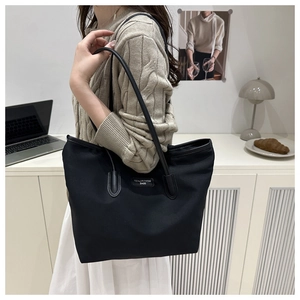 Close-up of black high-capacity tote bag with sleek shoulder straps and minimal logo detail