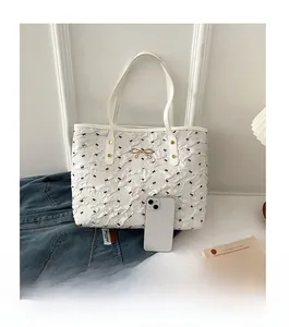 Comparaison de taille détaillée du sac cabas blanc à nœuds noirs avec un smartphone