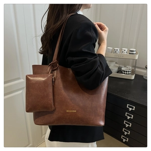 Detail view of large brown leather tote bag with a small detachable square charm