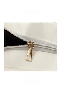 Gros plan d'une fermeture éclair dorée lisse sur un sac cabas blanc en cuir de qualité