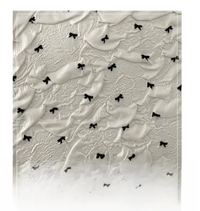 Détail du tissu plissé crème avec petits nœuds noirs pour un sac cabas tendance