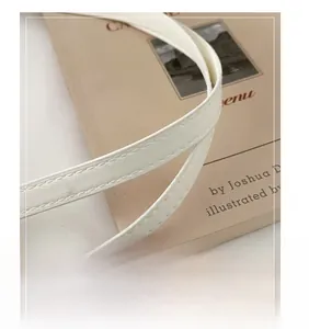 Gros plan sur la poignée en cuir confortable et les coutures de ce sac cabas blanc