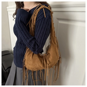 Primer plano de bolso hobo de ante marrón con flecos largos en una modelo real