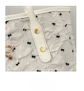 Détail des poignées renforcées avec rivets dorés sur un sac cabas blanc texturé